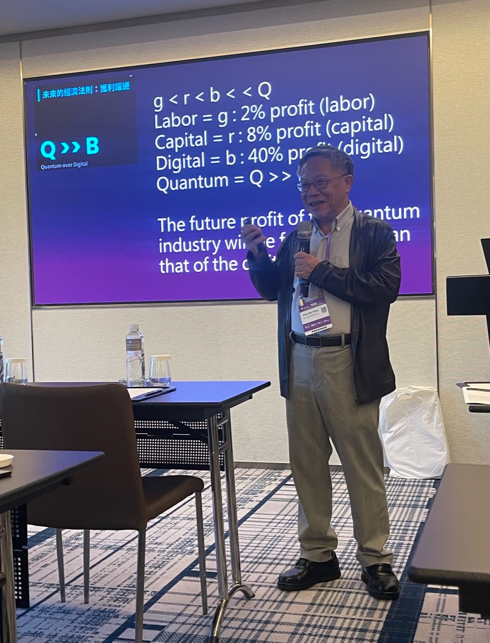 A speaker uses a microphone and slides to discuss the quantum industry